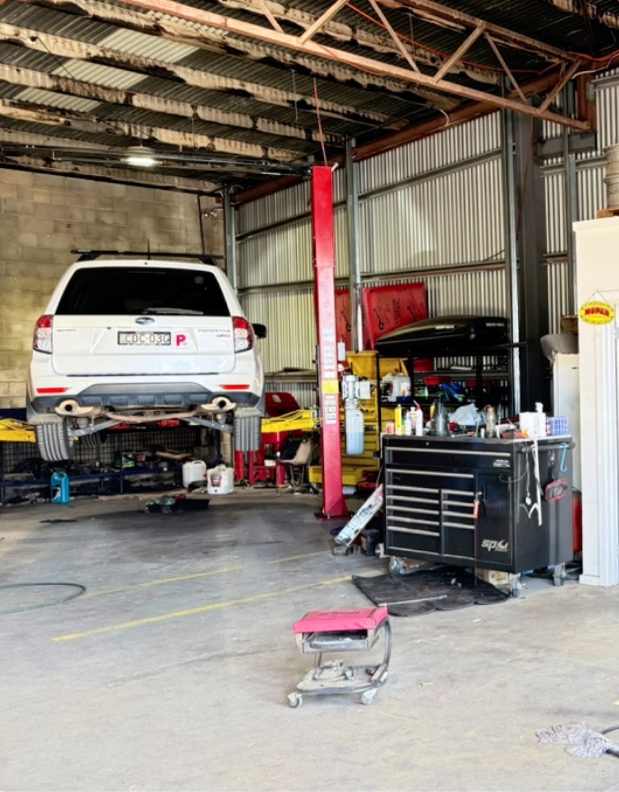 A car up on the two post hoist inside the R/T Automotive workshop, tool chest alongside