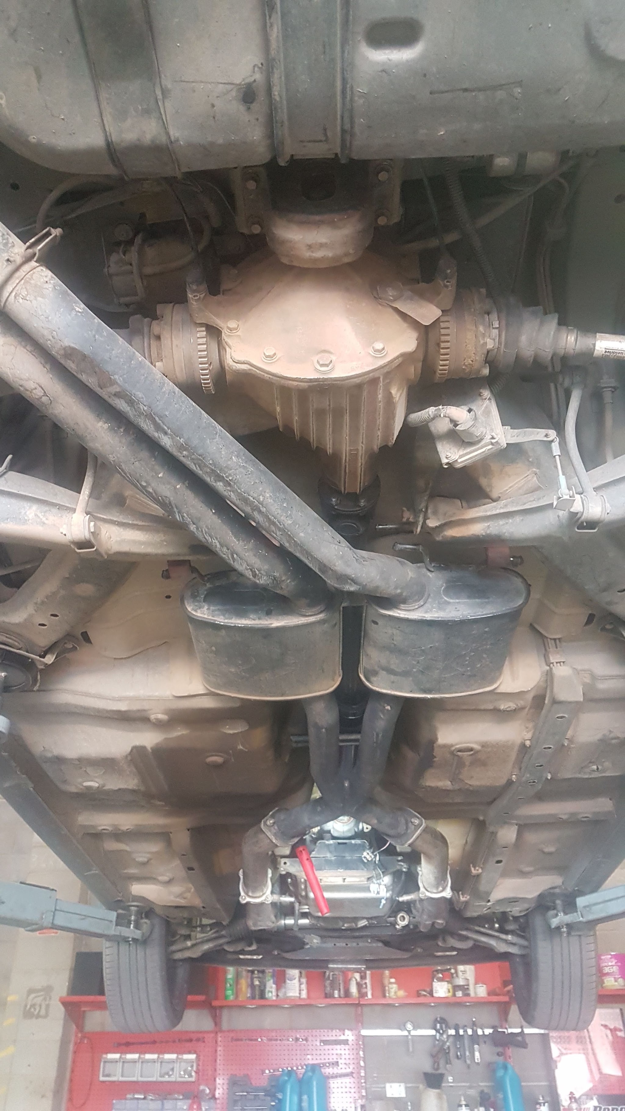 Underside of a car up on the hoist at R/T Automotive, exhaust and driveline in view